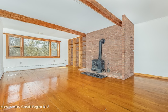 unfurnished living room with a baseboard heating unit, built in shelves, a wood stove, wood-type flooring, and beam ceiling