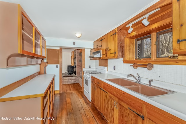 kitchen with under cabinet range hood, light countertops, a wood stove, a sink, and white range with gas cooktop