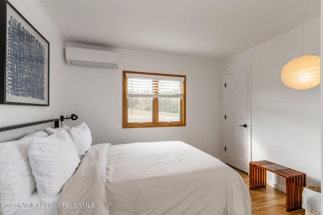 bedroom featuring ornamental molding, a wall unit AC, and wood finished floors