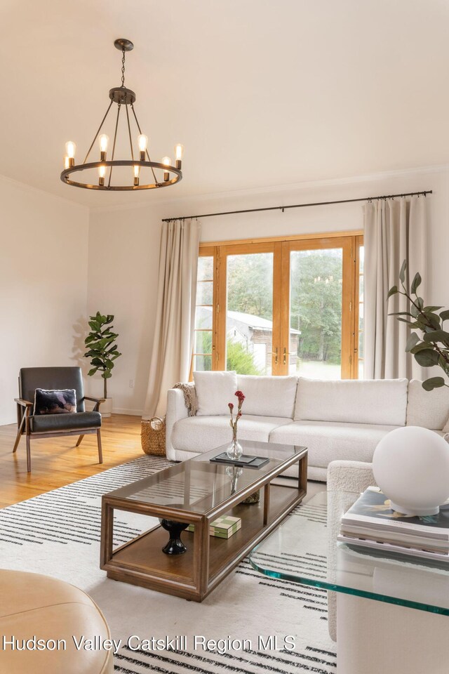living area with baseboards, a notable chandelier, and wood finished floors