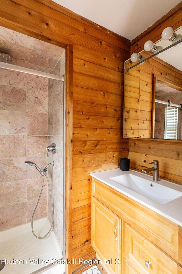 full bath with wood walls, a shower stall, and vanity