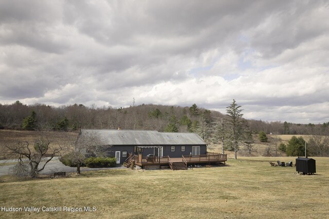 view of front of house featuring a forest view, a wooden deck, and a front yard