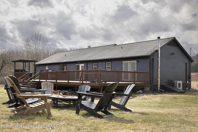 rear view of house with a lawn, a wooden deck, and a shingled roof