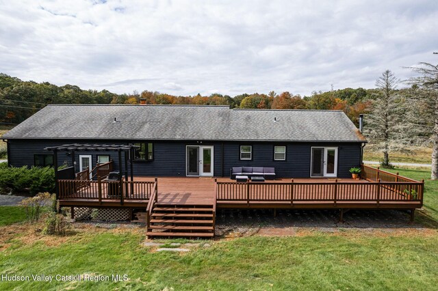rear view of property with a shingled roof, a deck, outdoor lounge area, french doors, and a yard