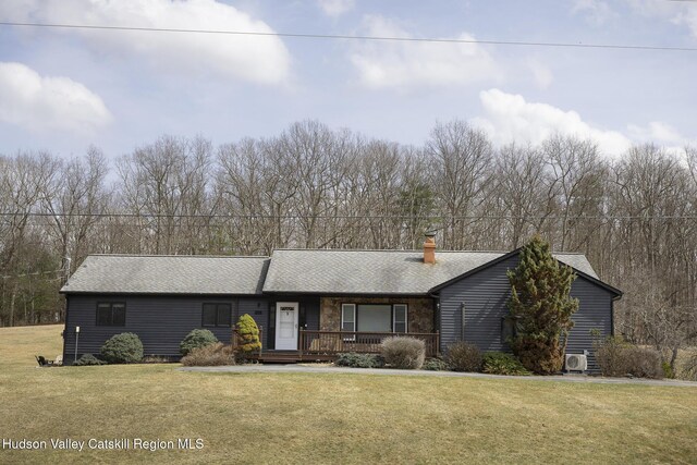 ranch-style house with covered porch, a chimney, roof with shingles, a front yard, and ac unit