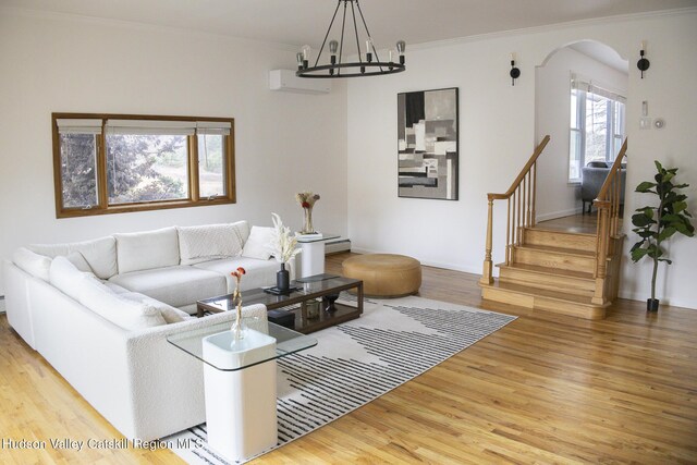 living room with wood finished floors, ornamental molding, arched walkways, and a wall unit AC