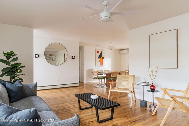 living area featuring an AC wall unit, a ceiling fan, a baseboard heating unit, and wood finished floors