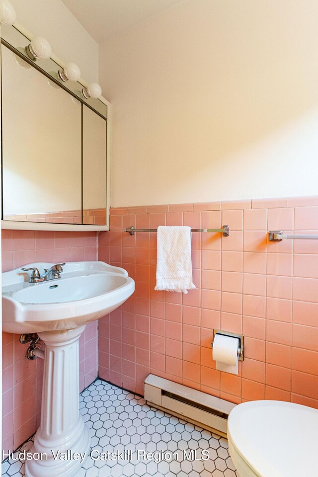 bathroom featuring a baseboard radiator, a wainscoted wall, toilet, and tile walls