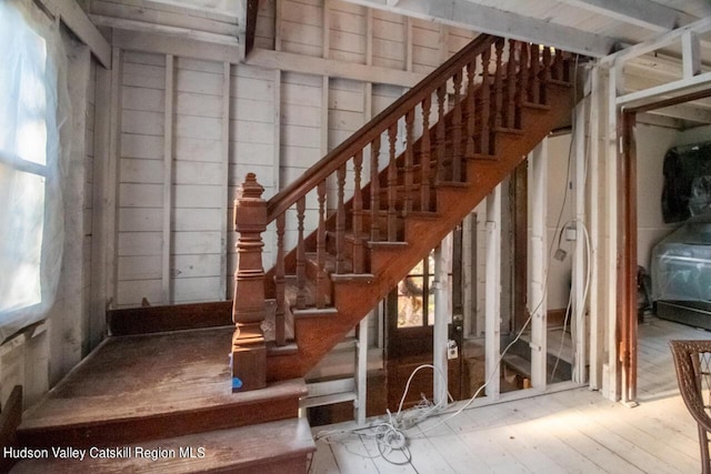 staircase featuring hardwood / wood-style flooring and wooden walls