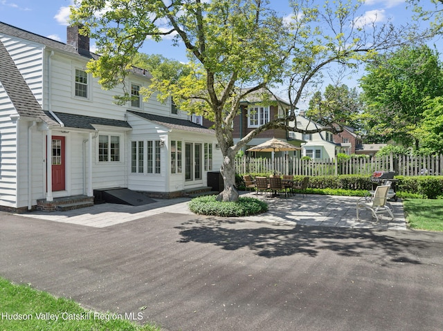 242 N Manor Ave, Kingston, NY 12401 - view of front facade with a patio area, a shingled roof, a chimney, entry steps, and outdoor dining space