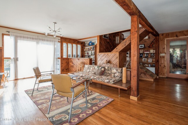 living room with wooden walls, a chandelier, and hardwood / wood-style flooring