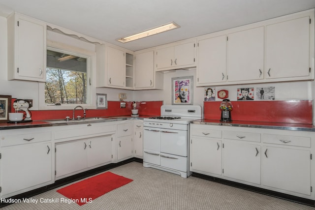 kitchen featuring white cabinets, white gas range oven, and sink