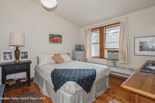 bedroom with hardwood / wood-style floors, cooling unit, and vaulted ceiling