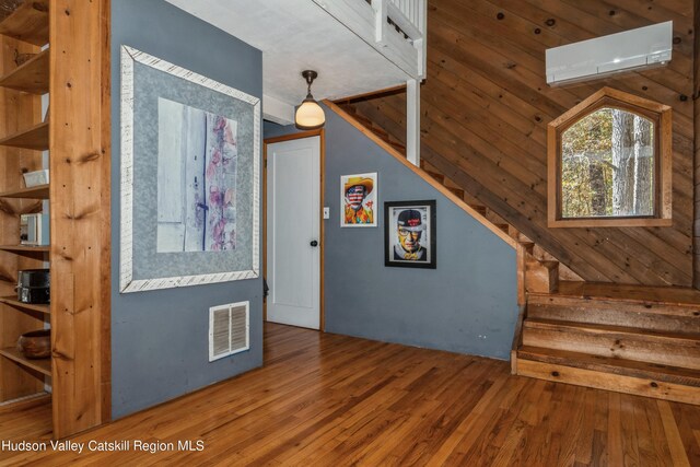 interior space featuring hardwood / wood-style floors, wood walls, and a wall mounted air conditioner