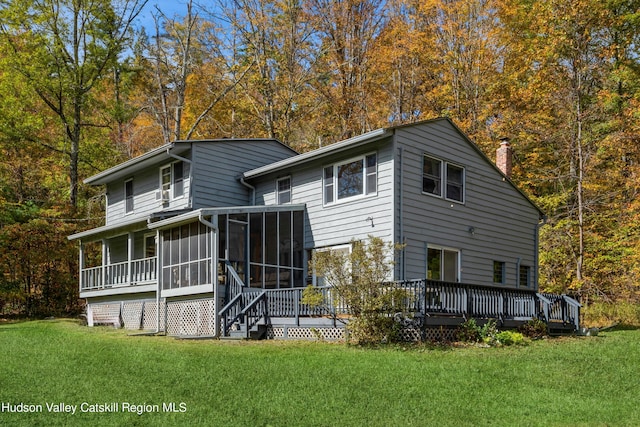 back of property with a sunroom, a yard, and a wooden deck