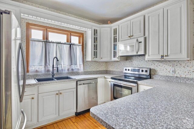 3630 Main St, Stone Ridge, NY 12484 - kitchen featuring appliances with stainless steel finishes, a sink, white cabinetry, and light wood-type flooring