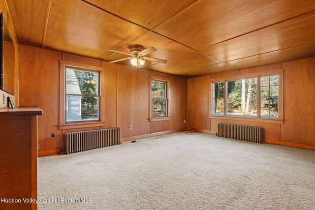 spare room with wood walls, wooden ceiling, and radiator