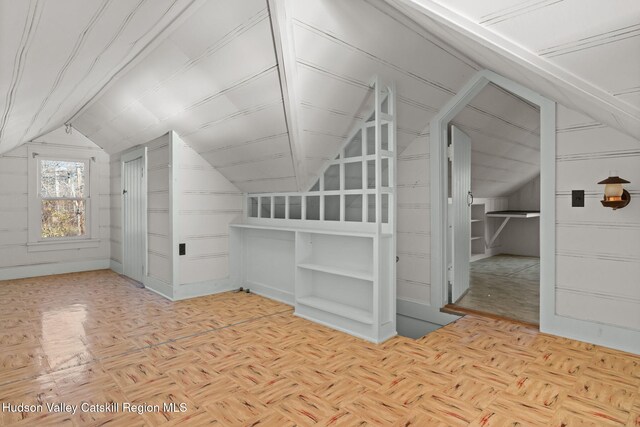 bonus room featuring light parquet flooring, wooden walls, and vaulted ceiling