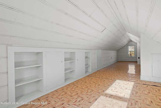 bonus room featuring built in features, light parquet floors, and vaulted ceiling