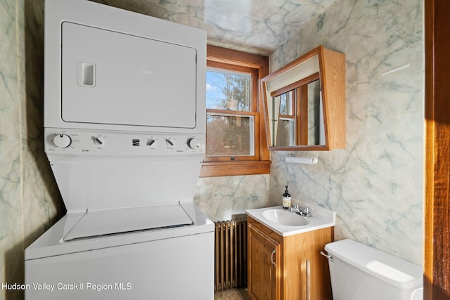 washroom with stacked washer and dryer, radiator, and sink