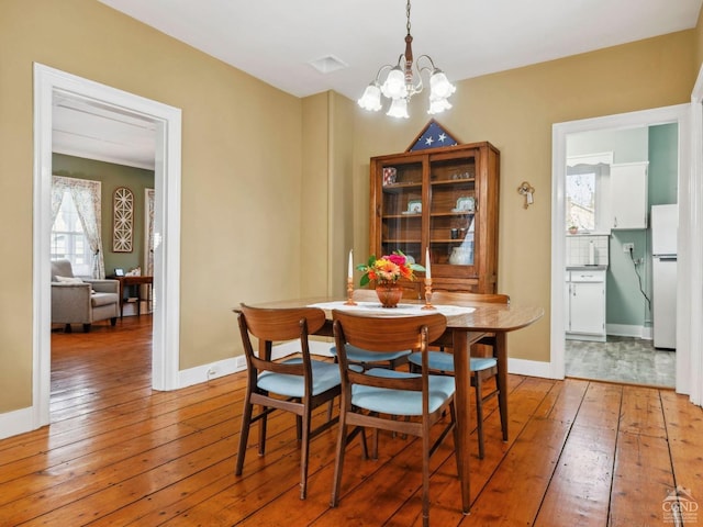 dining space featuring hardwood / wood-style flooring, a chandelier, and baseboards