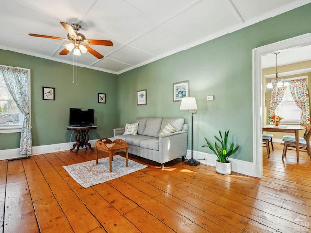 living room with healthy amount of natural light, wood-type flooring, a ceiling fan, baseboards, and crown molding