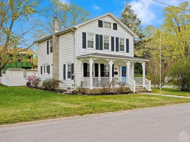 view of front of house featuring covered porch, a chimney, and a front yard