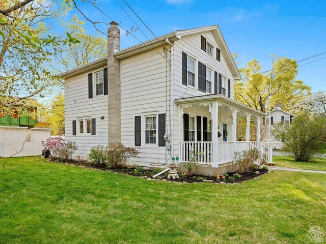 back of house featuring a porch, a chimney, and a lawn