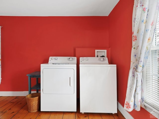 clothes washing area featuring independent washer and dryer, wood-type flooring, and baseboards