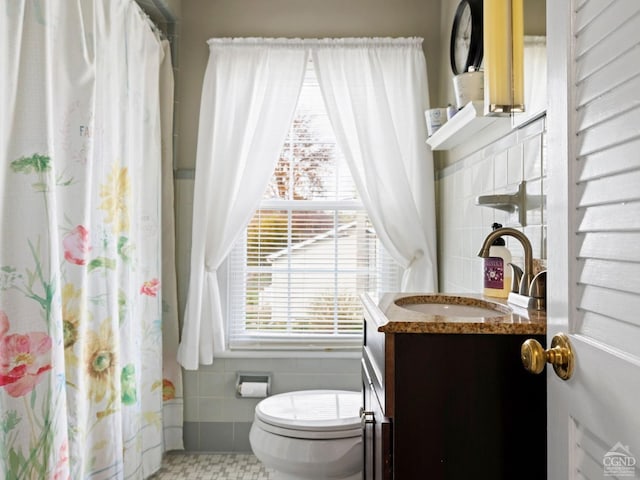 bathroom featuring tile walls, toilet, vanity, and curtained shower