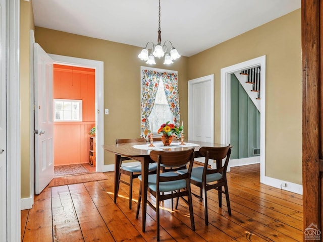 dining area featuring hardwood / wood-style floors, a chandelier, and baseboards