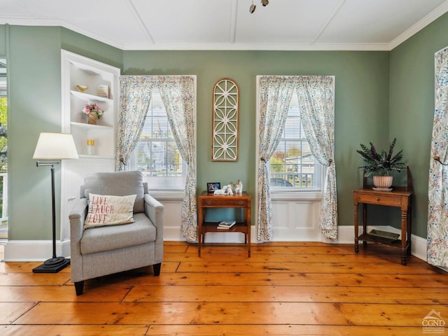 living area featuring wood-type flooring, ornamental molding, and baseboards
