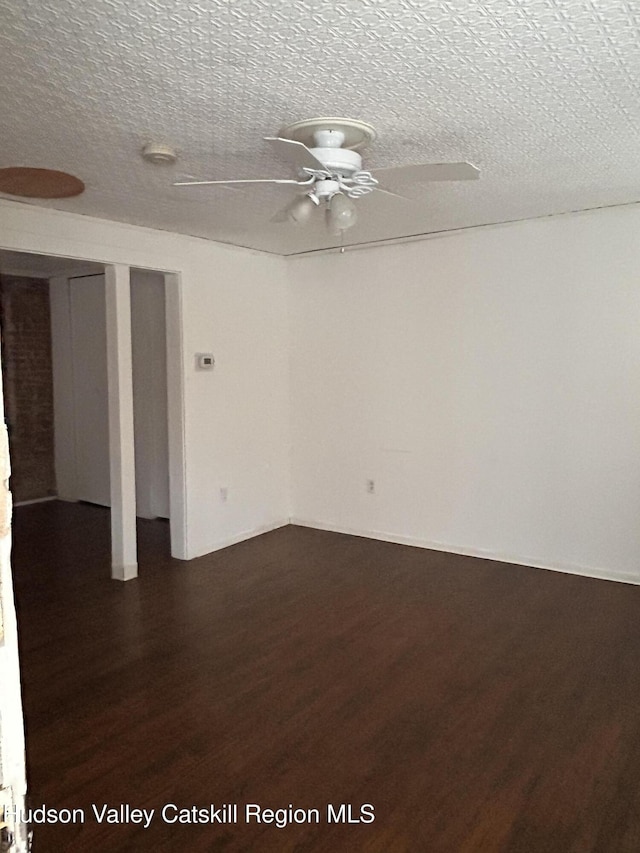 unfurnished room with ceiling fan, a textured ceiling, and dark wood finished floors