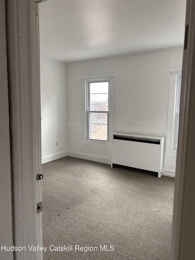 carpeted spare room with radiator heating unit and baseboards