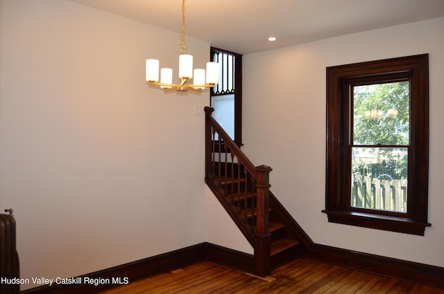 stairway featuring hardwood / wood-style floors and a notable chandelier