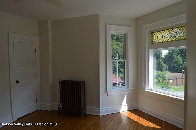 unfurnished room with dark hardwood / wood-style floors and radiator