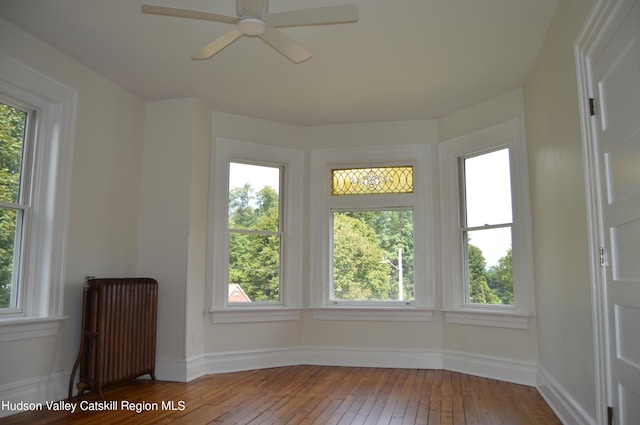 unfurnished sunroom featuring radiator heating unit and ceiling fan