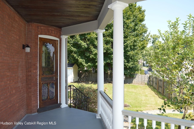 view of exterior entry featuring a lawn and a porch