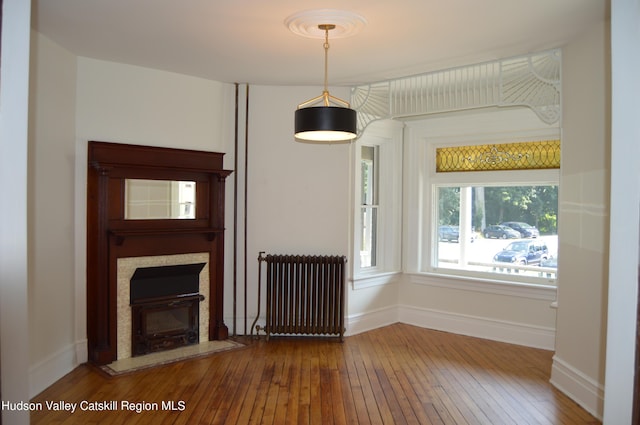 unfurnished living room with radiator and wood-type flooring