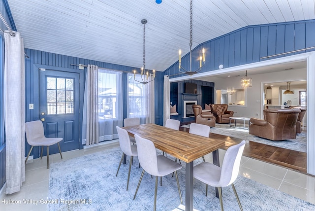 dining room featuring light tile patterned floors, plenty of natural light, a fireplace, and a chandelier