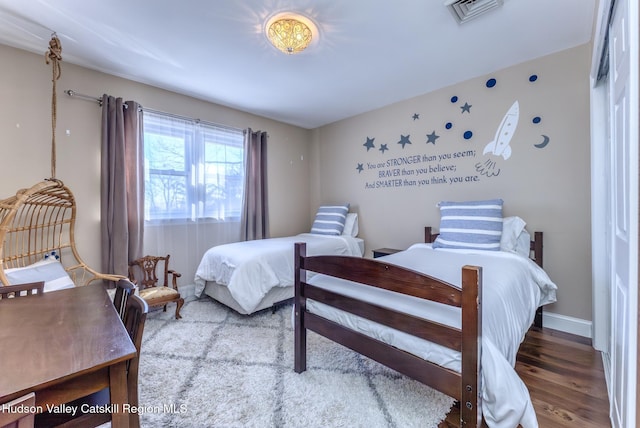 bedroom featuring baseboards, visible vents, and wood finished floors