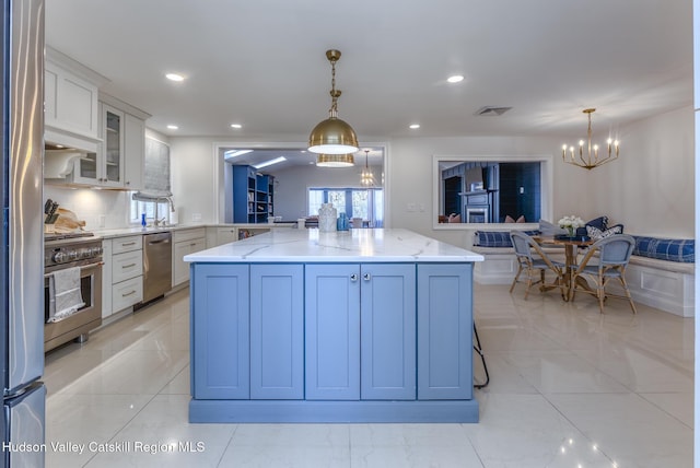 kitchen featuring white cabinets, glass insert cabinets, a center island, hanging light fixtures, and stainless steel appliances