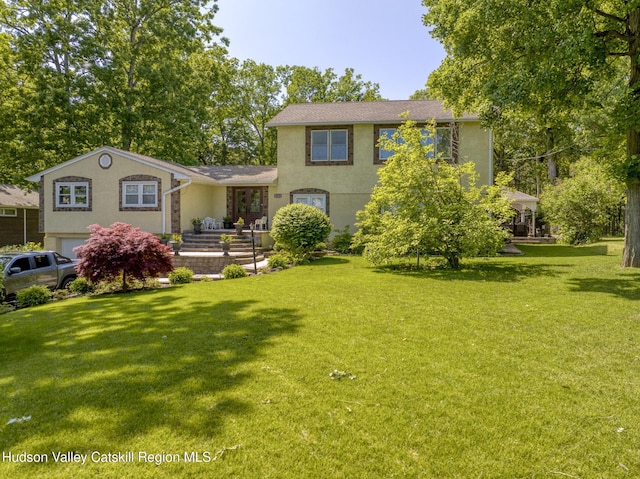rear view of property with a yard and stucco siding