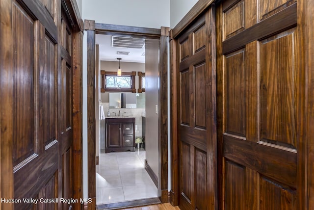 corridor featuring light tile patterned flooring, a sink, and visible vents