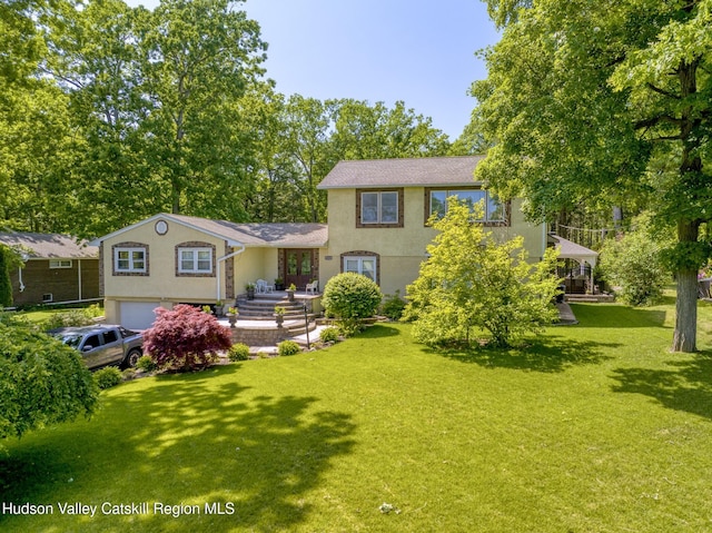 view of front of house with a front lawn, an attached garage, and stucco siding