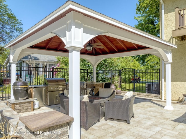 view of patio with a ceiling fan, area for grilling, a grill, fence, and a gazebo