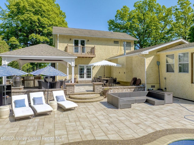 rear view of house with french doors, an outdoor living space with a fire pit, a balcony, a gazebo, and a patio area