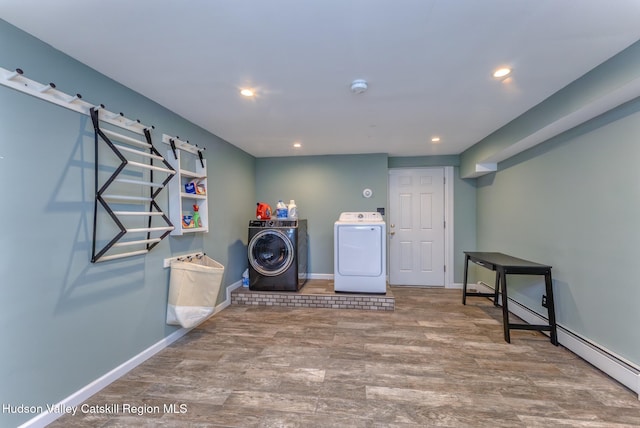 laundry area featuring laundry area, baseboards, washer and clothes dryer, a baseboard radiator, and wood finished floors