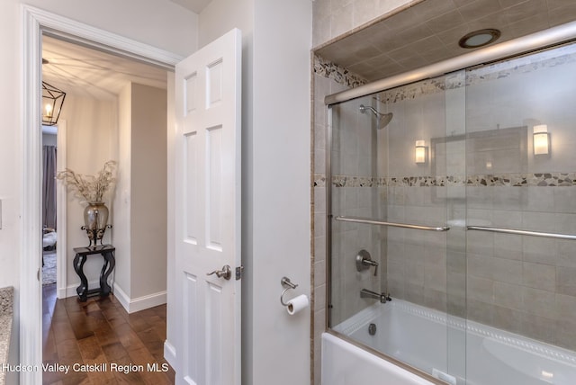 bathroom featuring enclosed tub / shower combo, wood finished floors, and baseboards