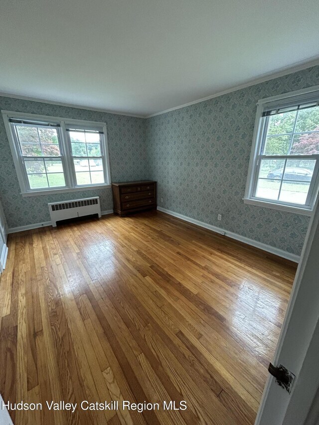 969 Blue Mountain Rd, Saugerties, NY 12477 - spare room featuring hardwood / wood-style flooring, wallpapered walls, radiator, and crown molding